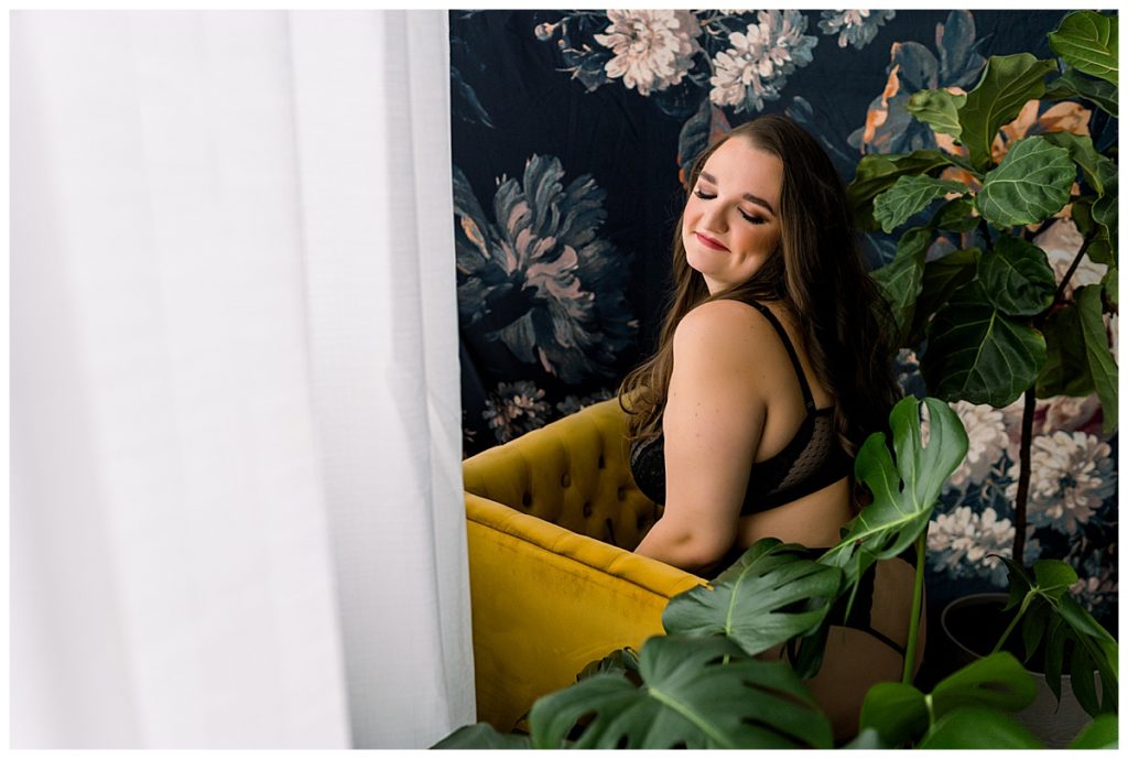 Woman leaning on yellow chair during empowering boudoir session