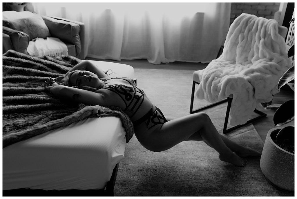 Woman lays against bed for South Dakota Boudoir Photographer 