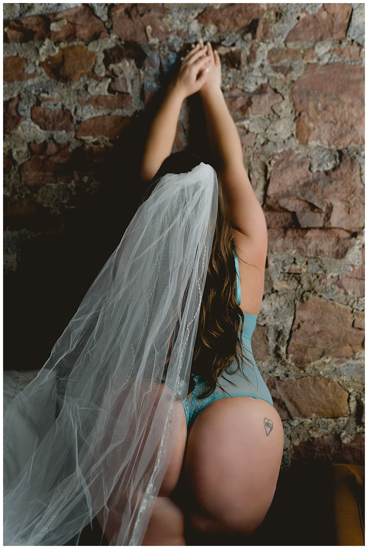 Woman leans up against wall with veil for Why You Need A Boudoir Session