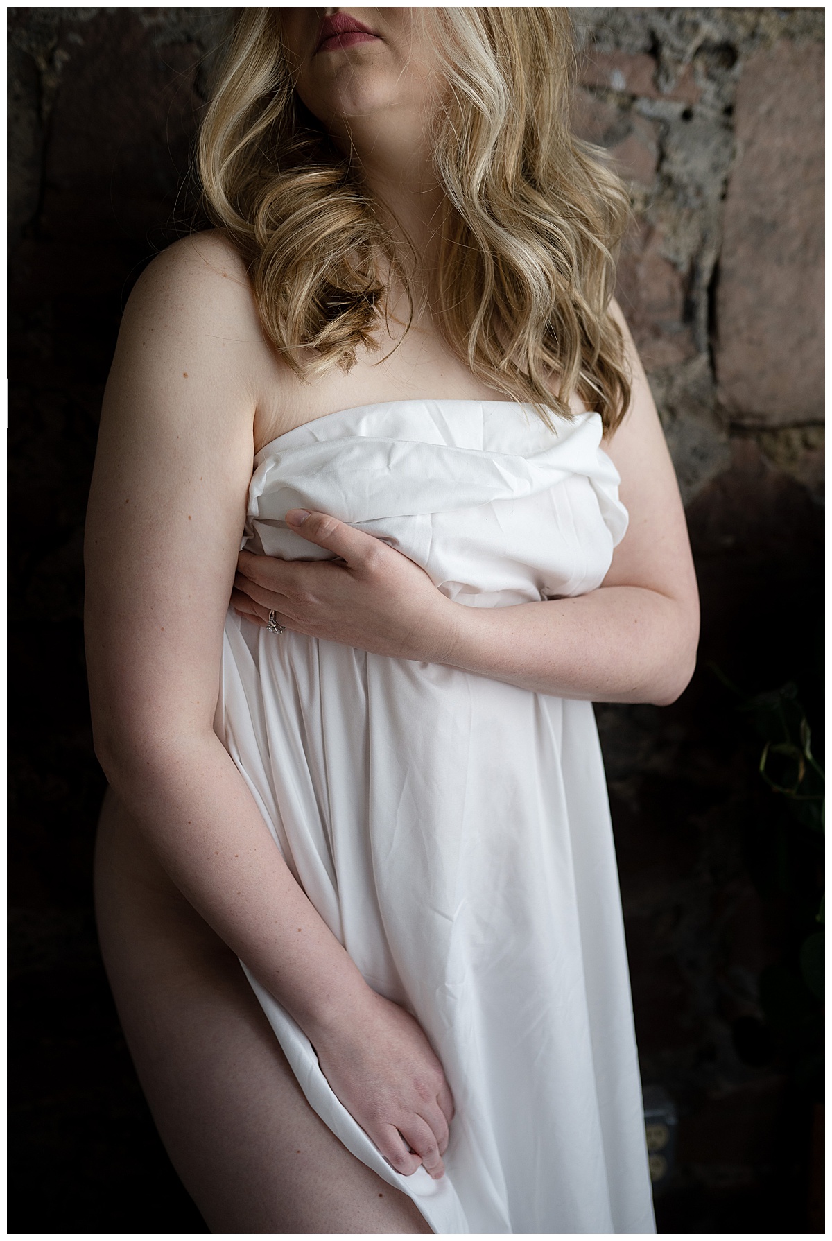 Woman holding white sheet covering body for Sioux Falls Boudoir Photographer