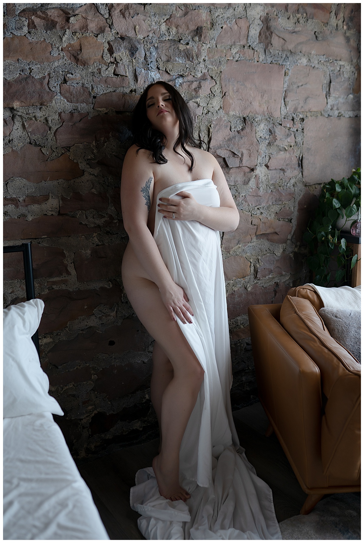 Lady covers body with sheet against wall for Emma Christine Photography