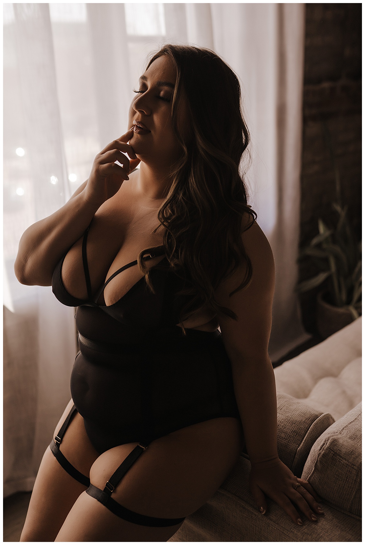 Adult sits on couch in black lingerie from one of the perfect Places to Buy Lingerie For Your Boudoir Session 