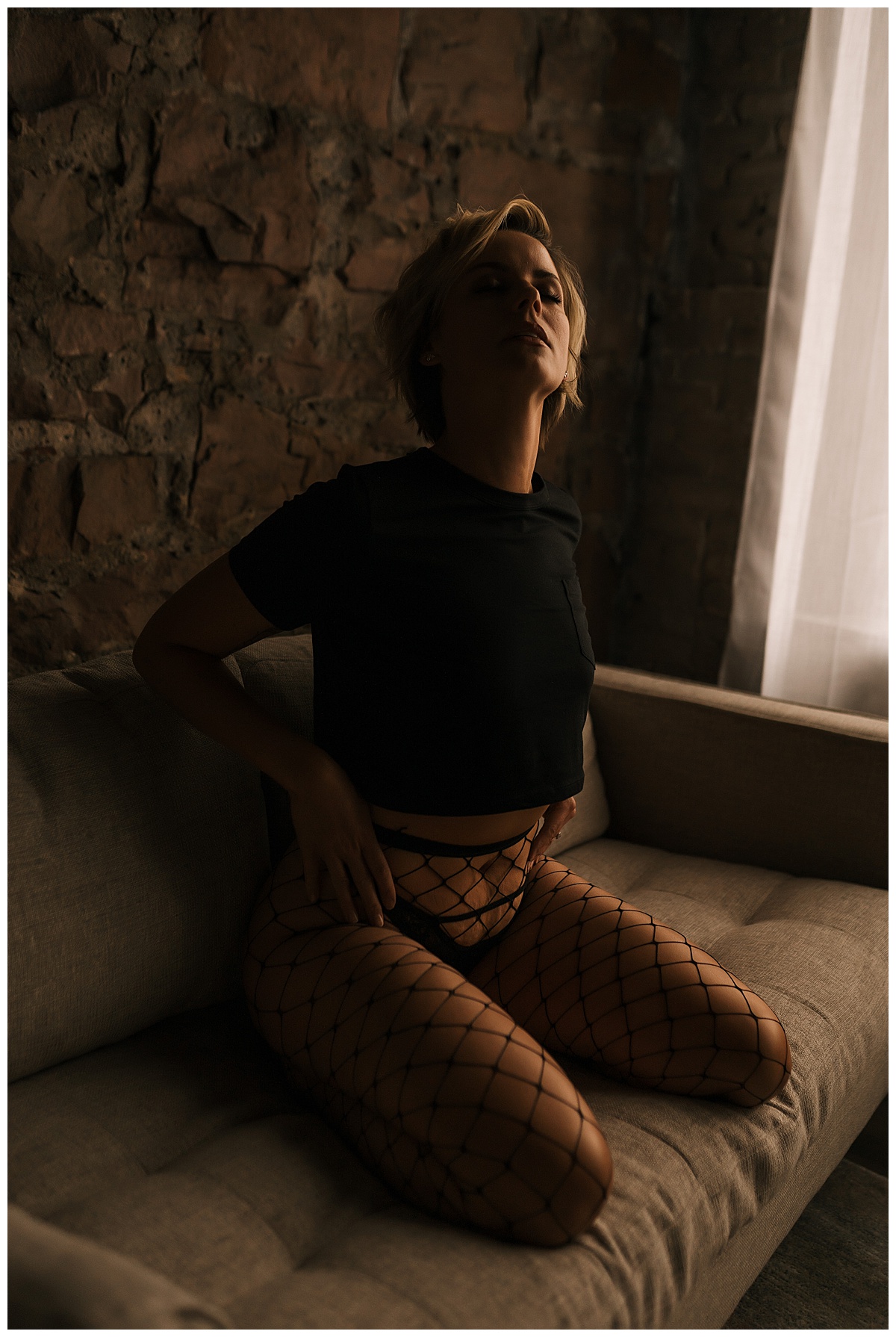 Woman sits on edge of couch Wearing Fishnets