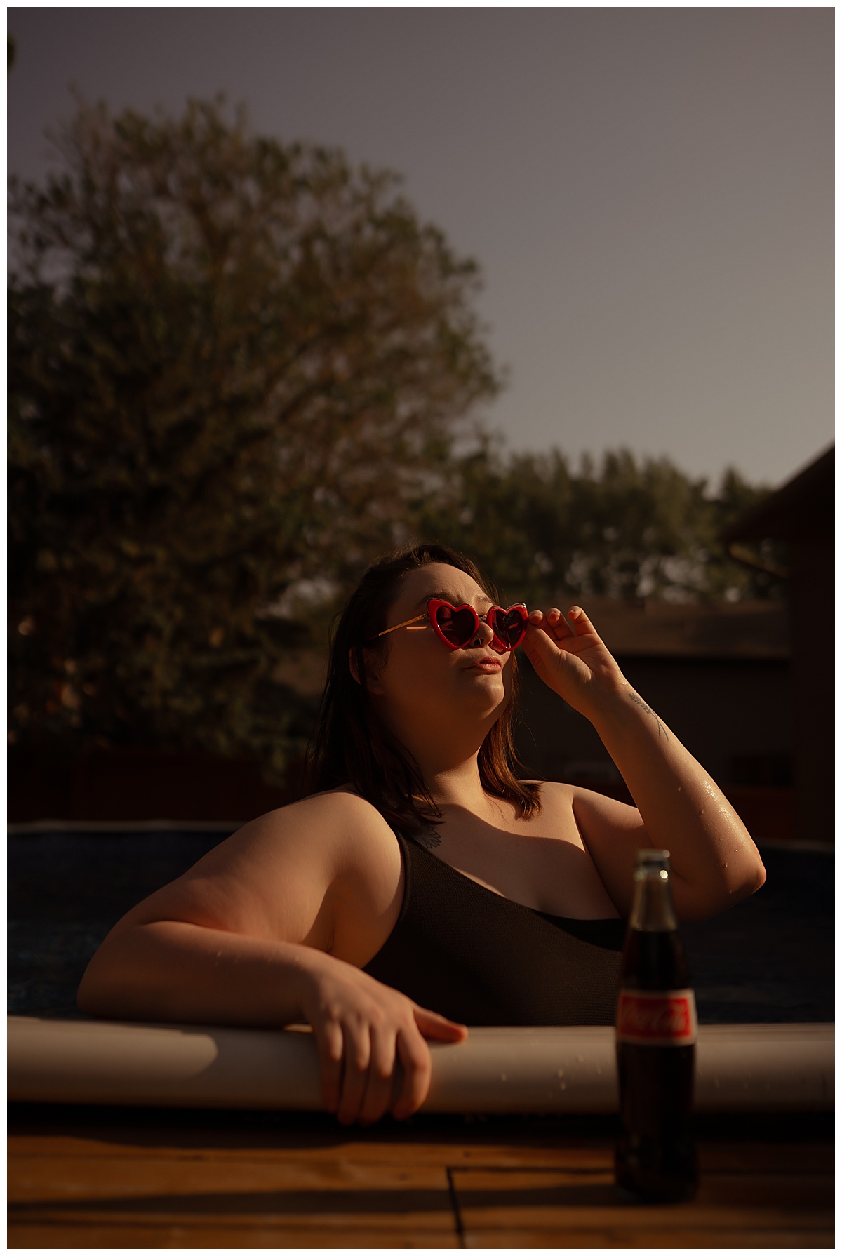 Person stands in pool with heart sunglasses for Emma Christine Photography
