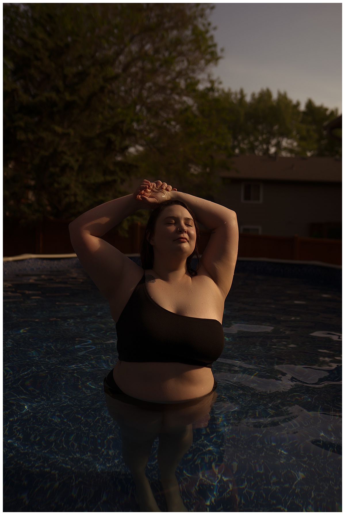 Girl holds hands crossed over hear head during a pool boudoir session