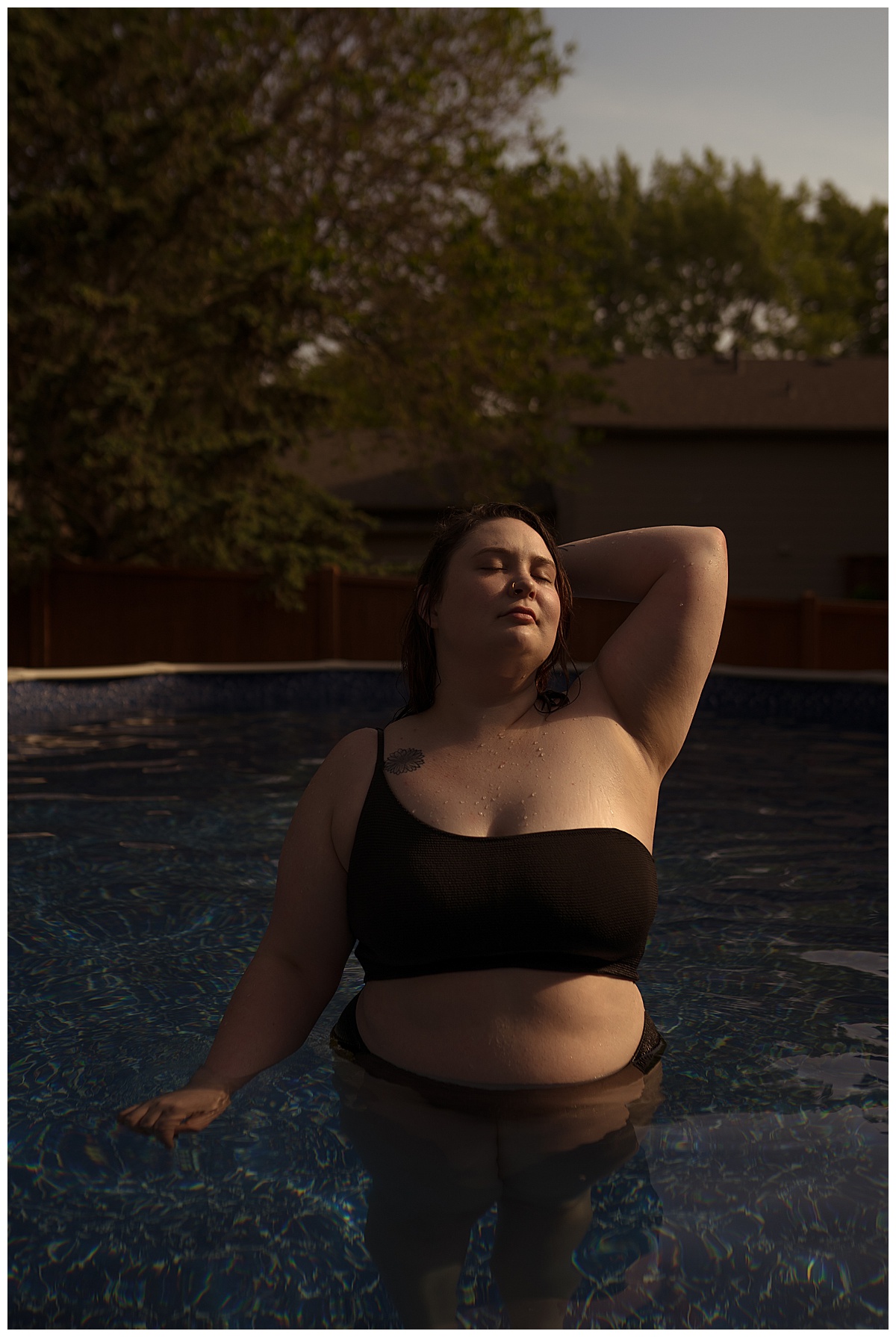 Lady holds arms behind her head in a black bathing suit for Emma Christine Photography