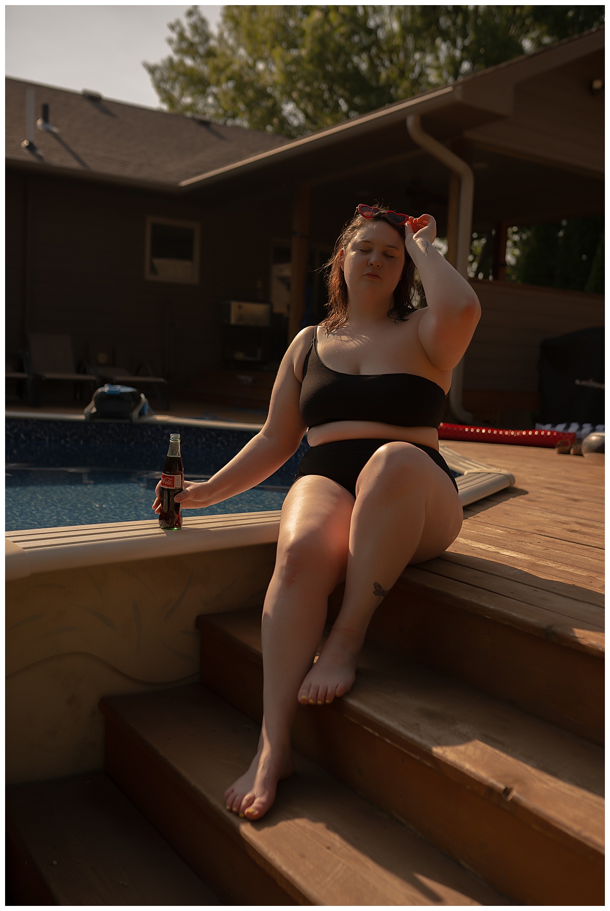 Person sits on deck stairs wearing a black bathing suit for Emma Christine Photography