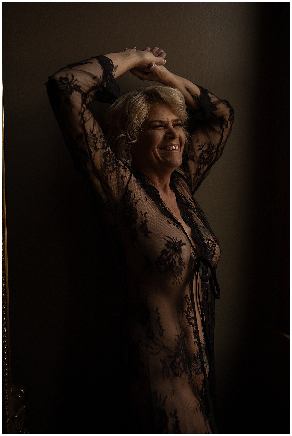 Adult shares a big smile wearing lingerie for Sioux Falls Boudoir Photographer