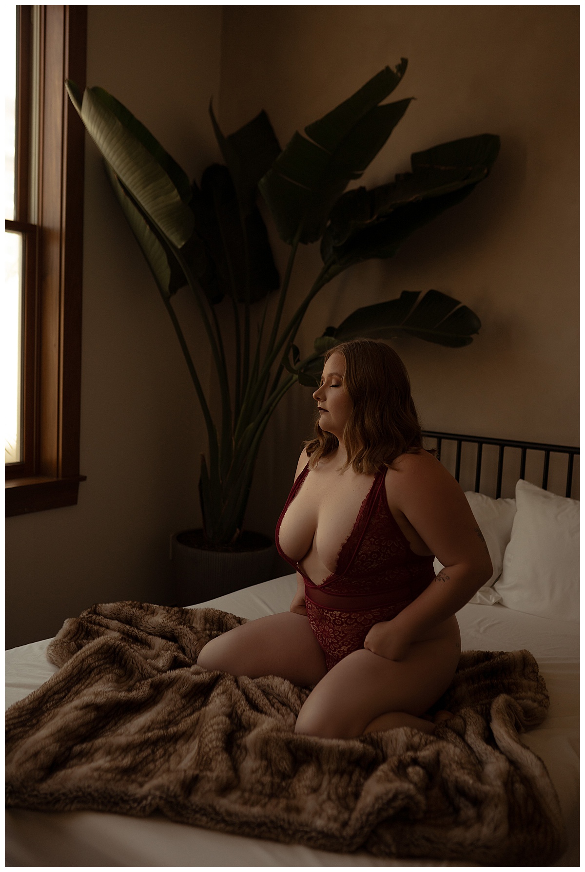 Woman kneels on the bed in red lingerie for Emma Christine Photography