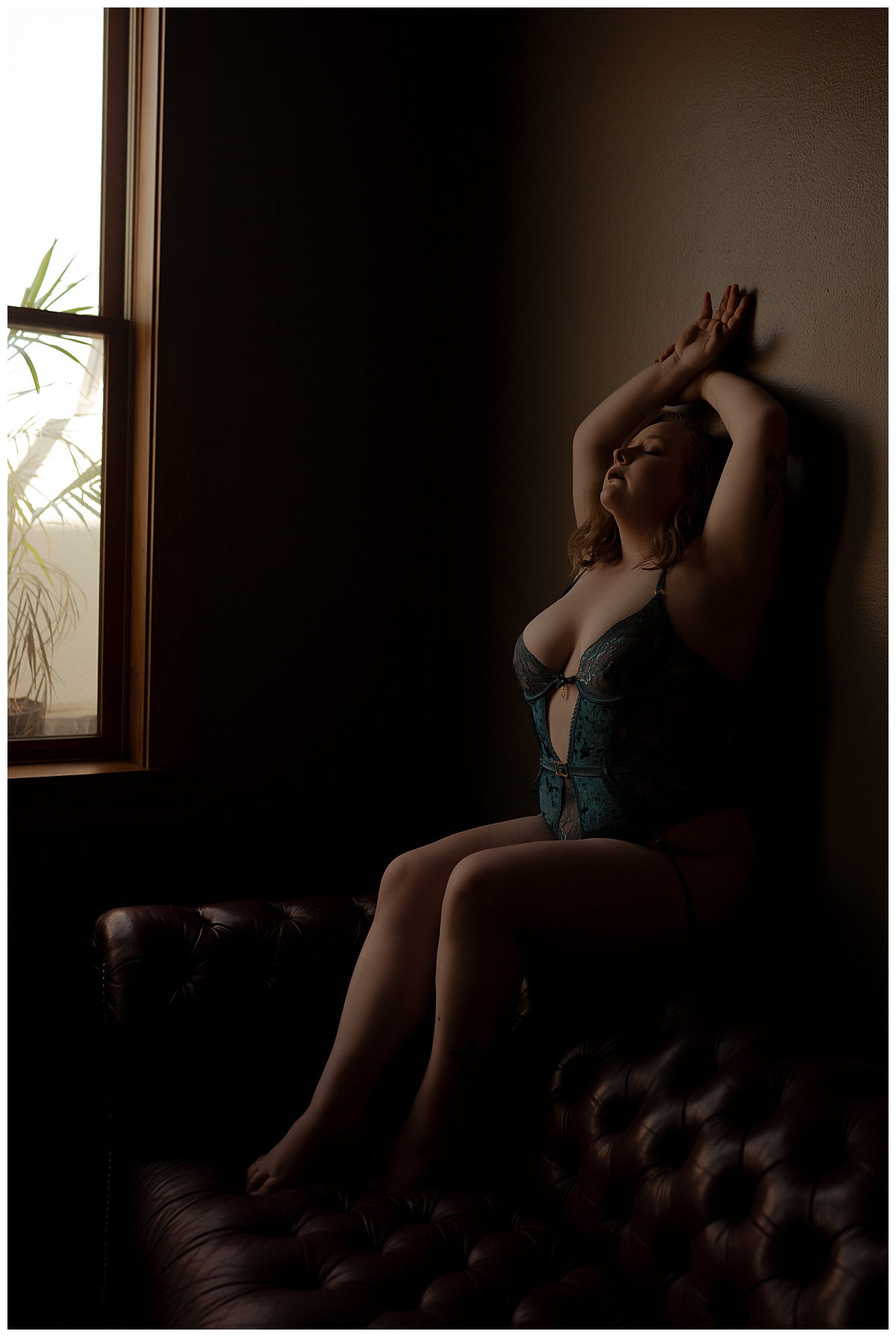 Person sits on the couch against the wall for Sioux Falls Boudoir Photographer