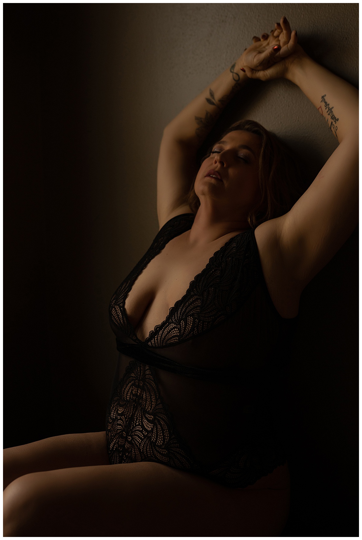 Woman holds hand above head in black lingerie for Emma Christine Photography
