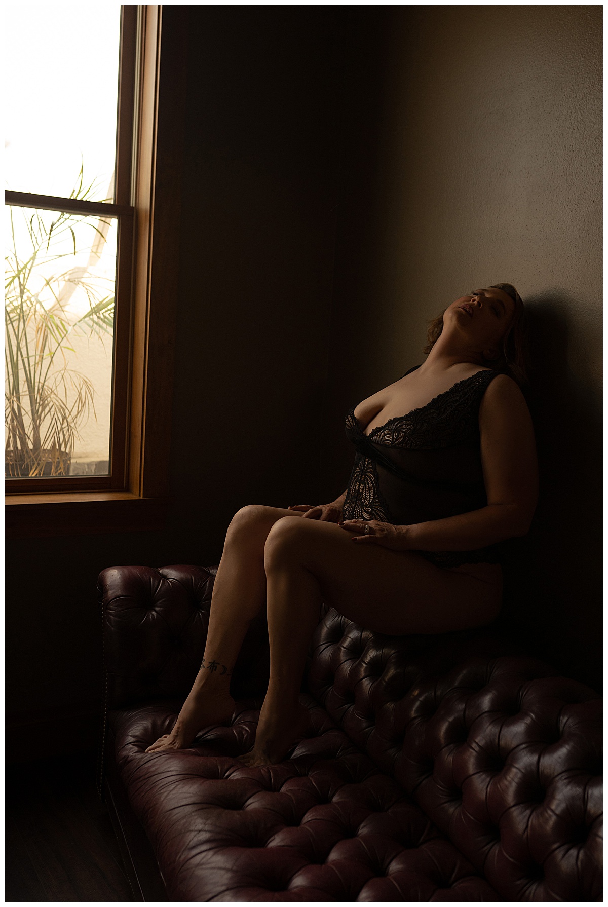 Girl sits on the couch wearing black lingerie for Sioux Falls Boudoir Photographer