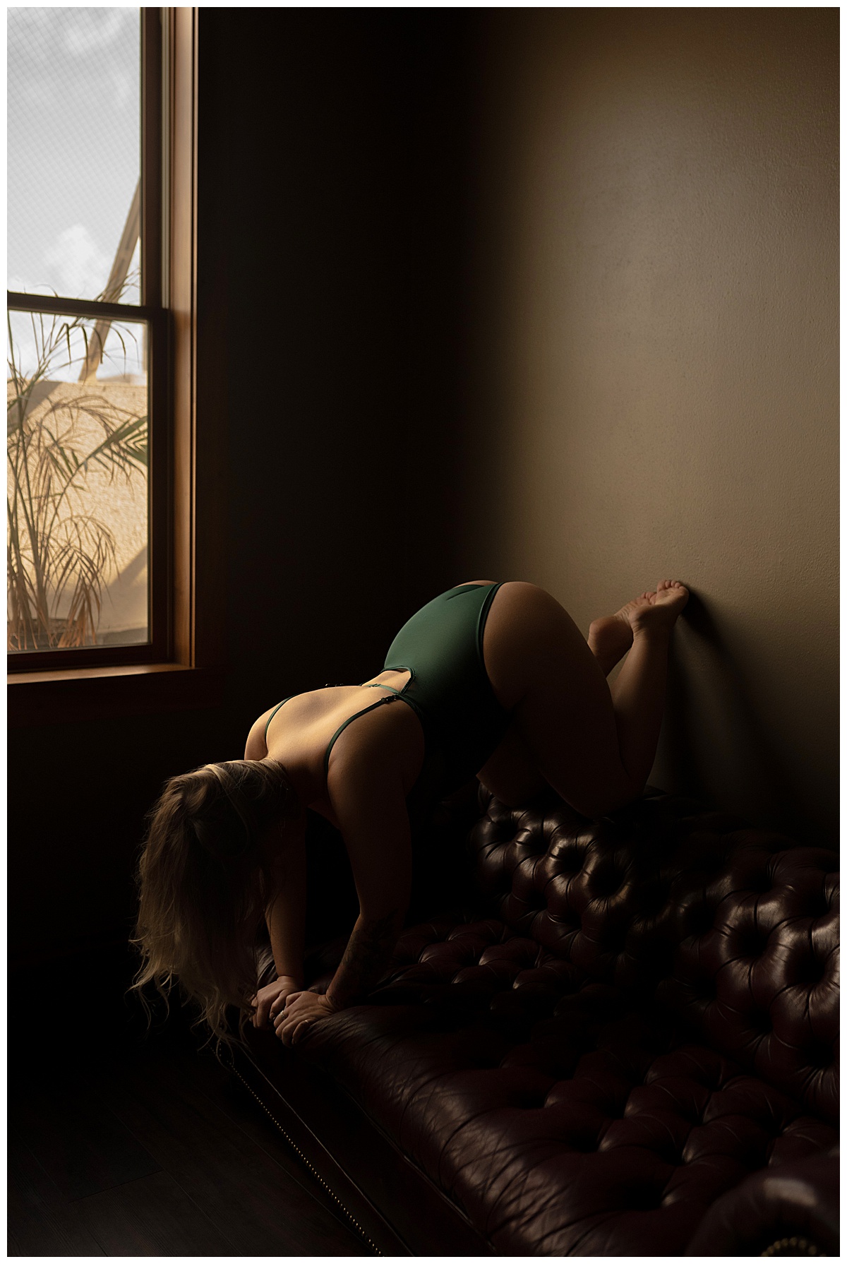Adult leans over the leather couch wearing lingerie for Sioux Falls Boudoir Photographer
