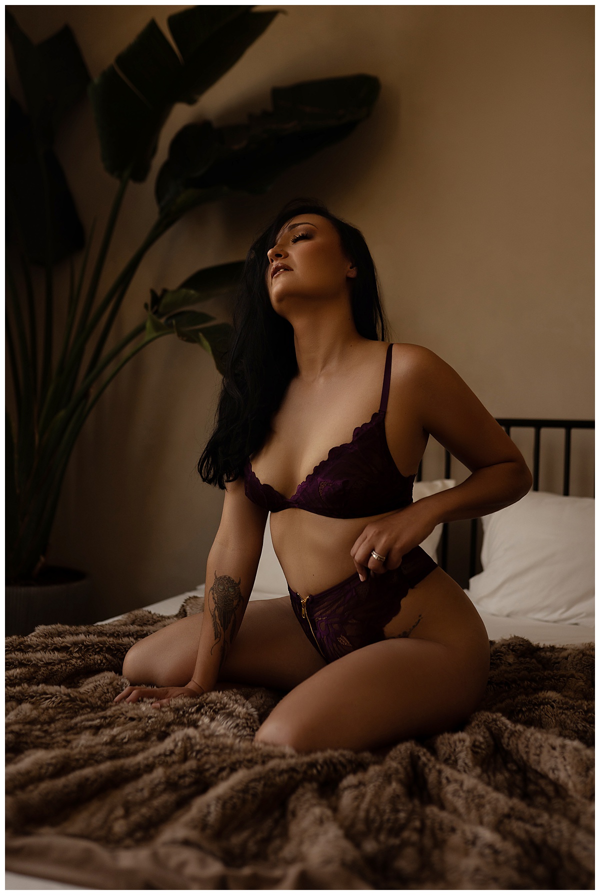 Adult kneels on bed tugging at lingerie for Sioux Falls Boudoir Photographer