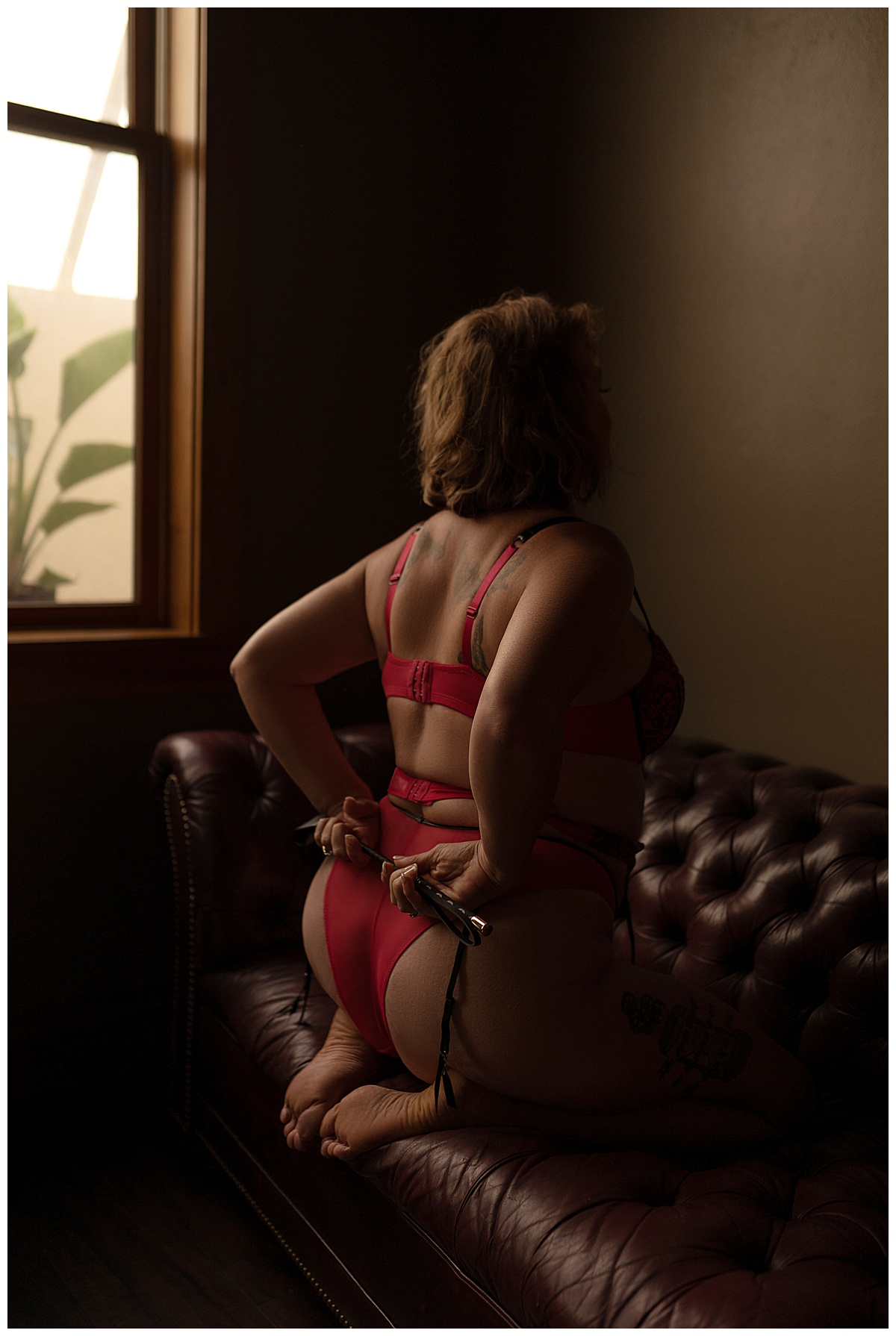Adult uses Props For A Boudoir Session and holds the whip behind her back wearing red lingerie 