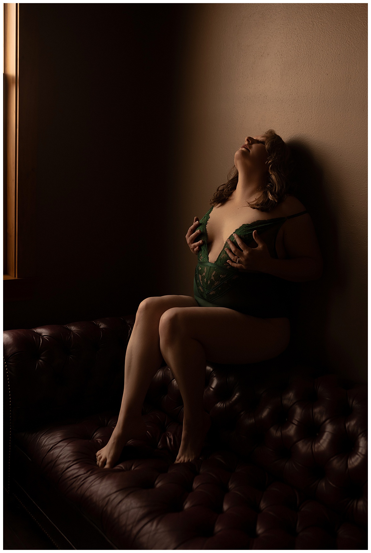 The adult covers chest with their arms and sits on a couch for Emma Christine Photography