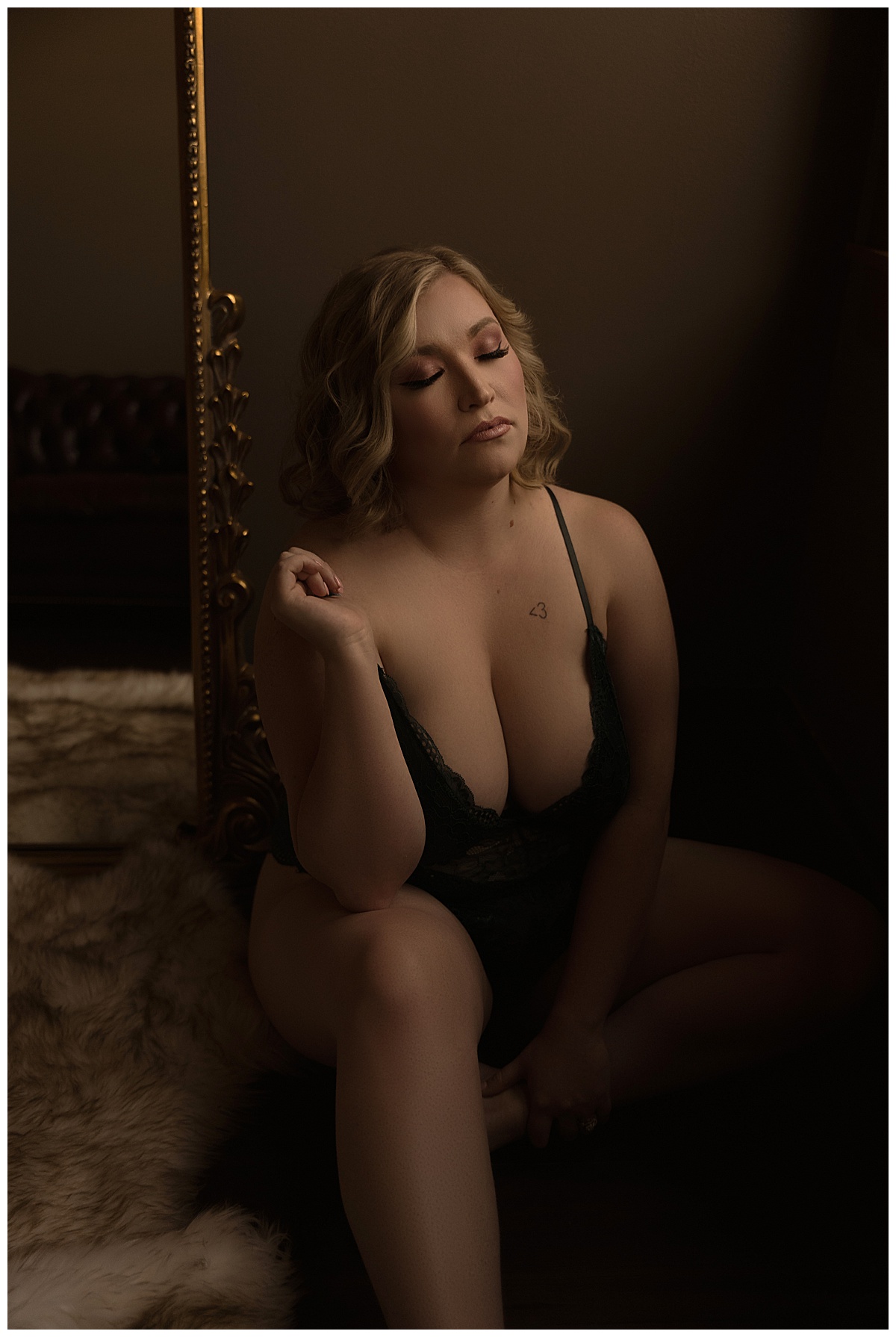 Female sits on the floor wearing black lace lingerie for Sioux Falls Boudoir Photographer