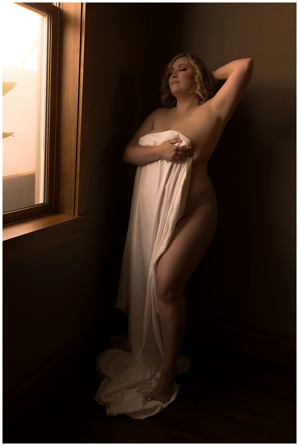 Woman covers her body with a white sheet for Sioux Falls Boudoir Photographer