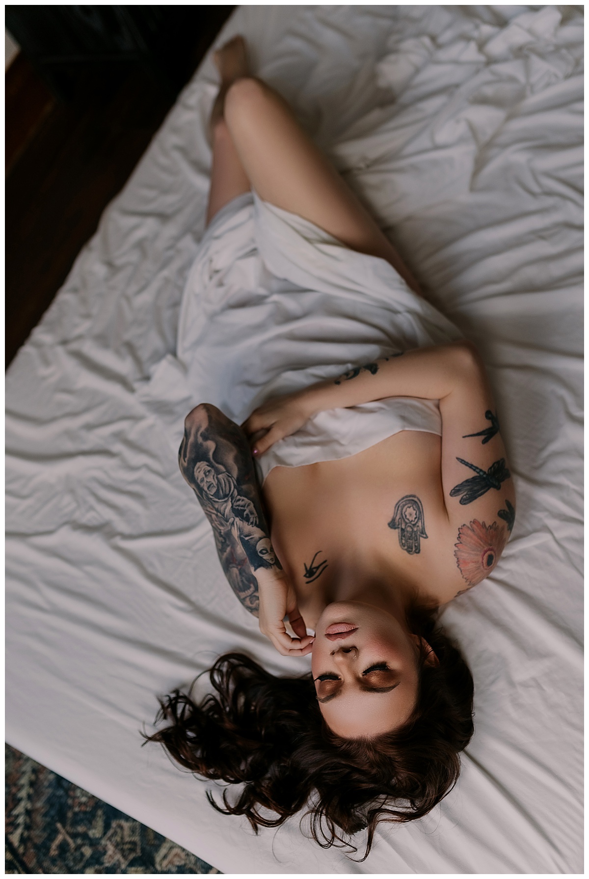 Adult lays on the bed wearing a white sheet for Sioux Falls Boudoir Photographer