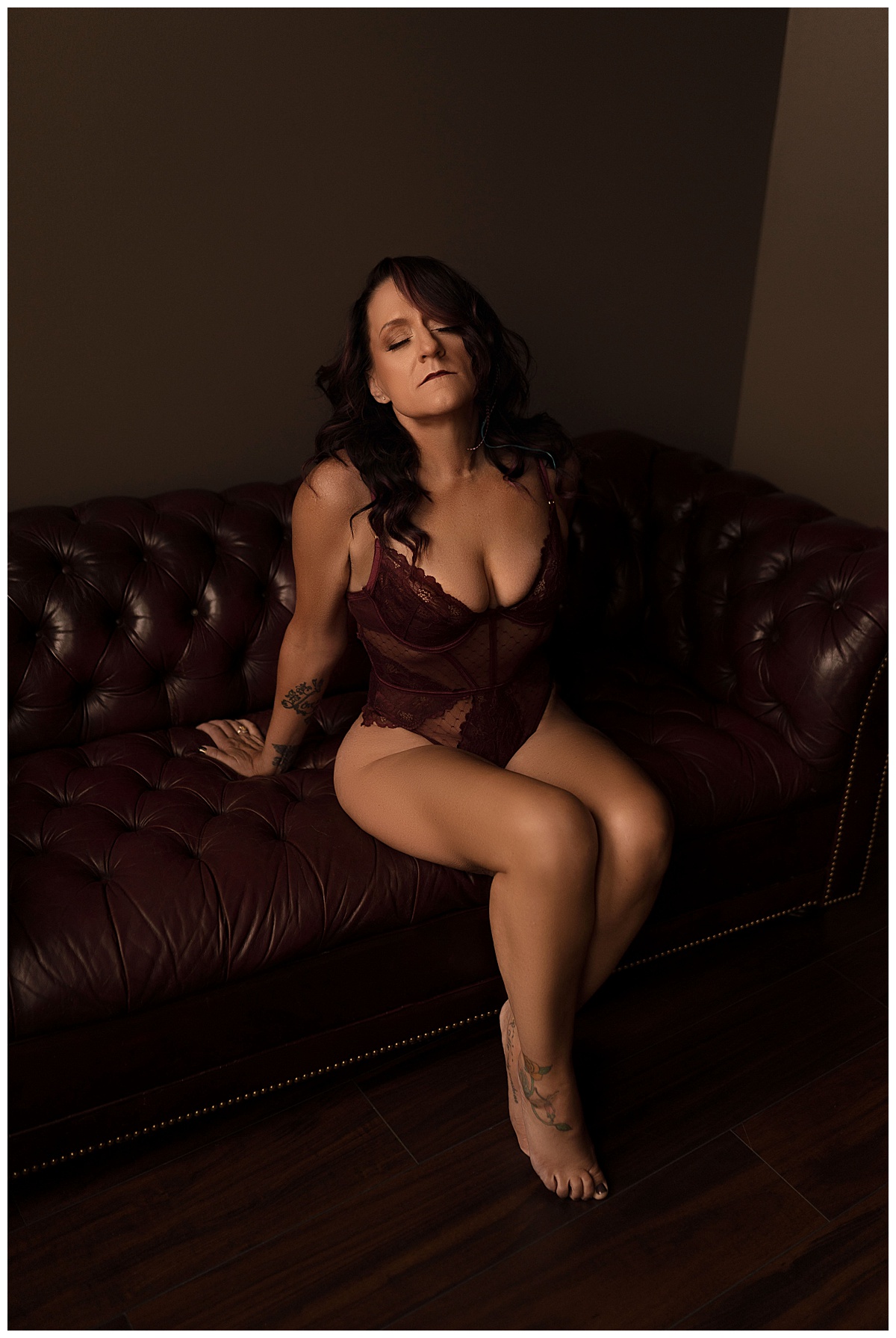 Adults sits on the edge of a couch wearing lingerie for Emma Christine Photography