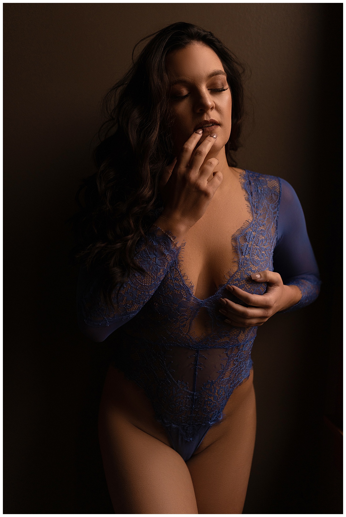 Woman covers her chest with her hands and touches her lip for Sioux Falls Boudoir Photographer