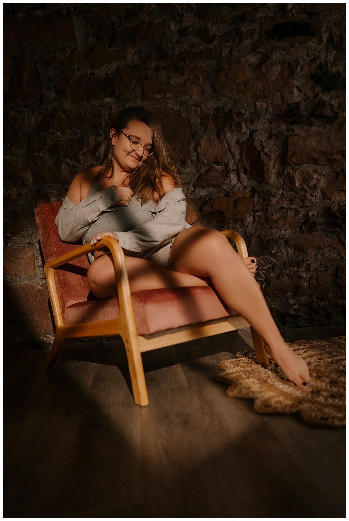 Woman sits on the chair wearing a cardigan during her cozy boudoir session