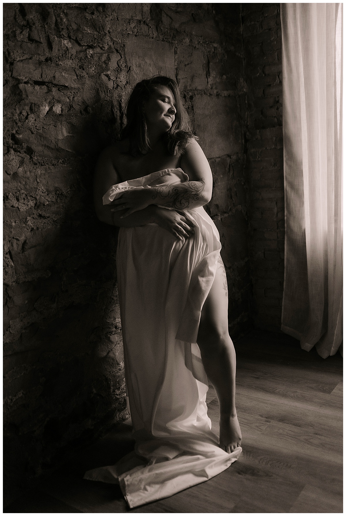 Girl stands against a wall wrapped in a sheet for Emma Christine Photography