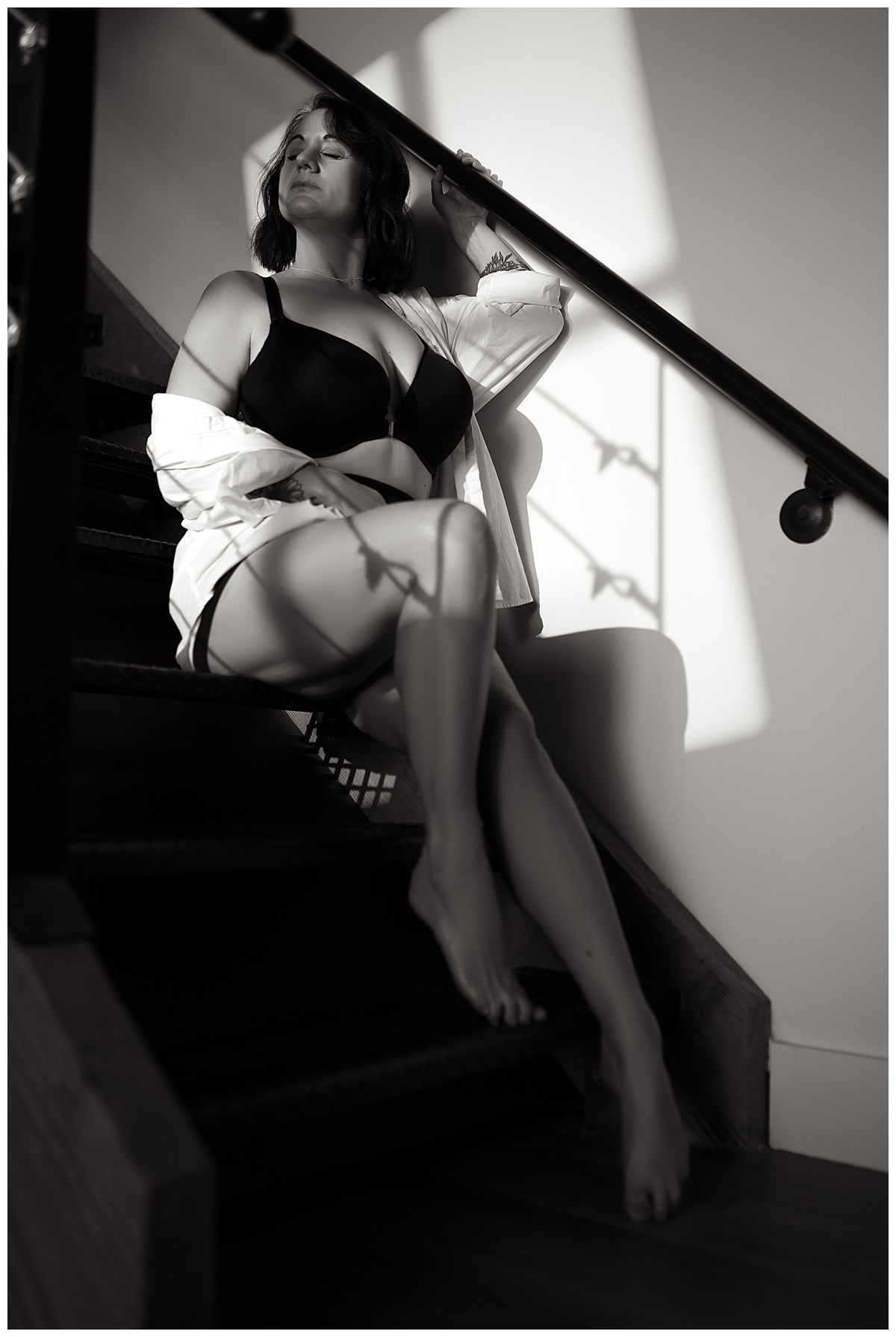 Woman sits on the steps wearing button up during her Pin-Up Inspired Boudoir Session