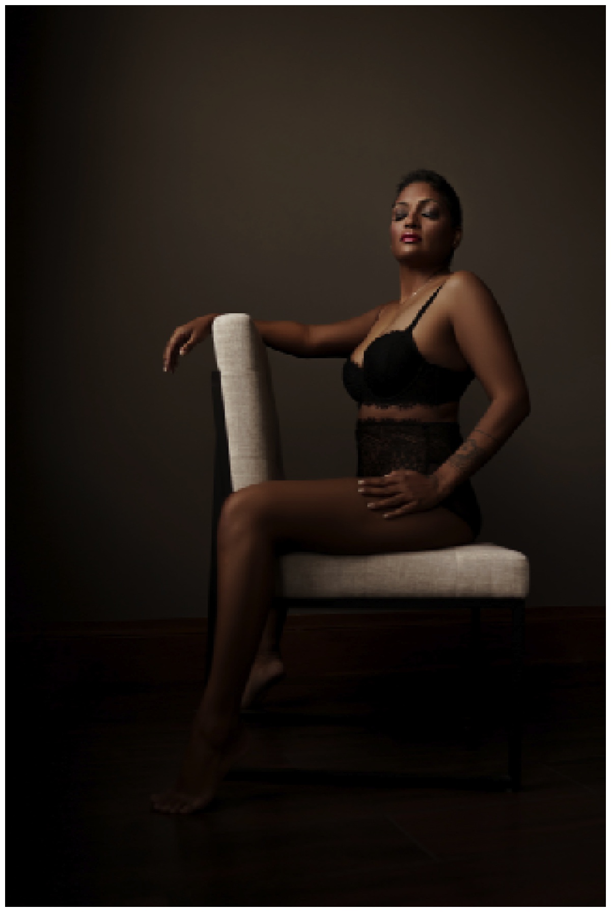 Adult sits on the chair wearing black lingerie for Emma Christine Photography