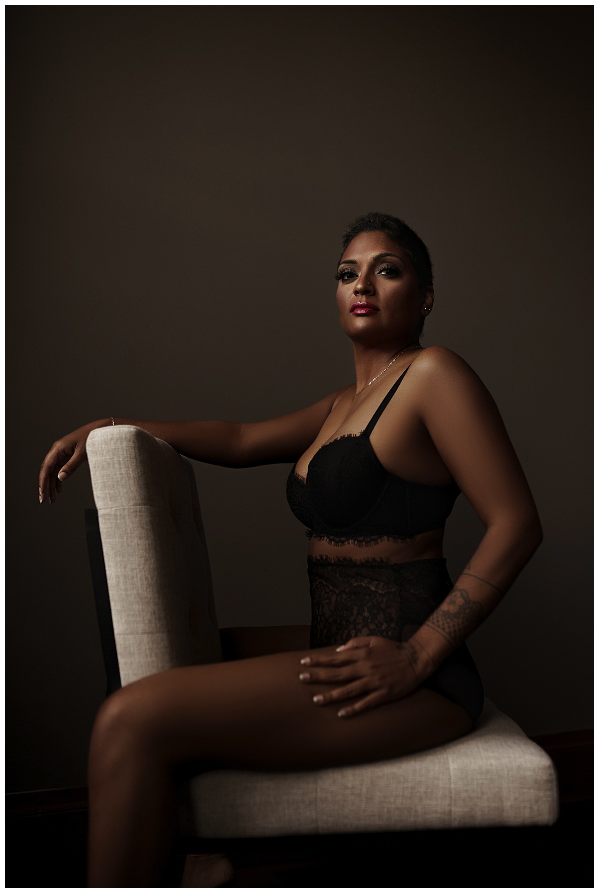 Adult sits on the chair wearing black lingerie for Sioux Falls Boudoir Photographer