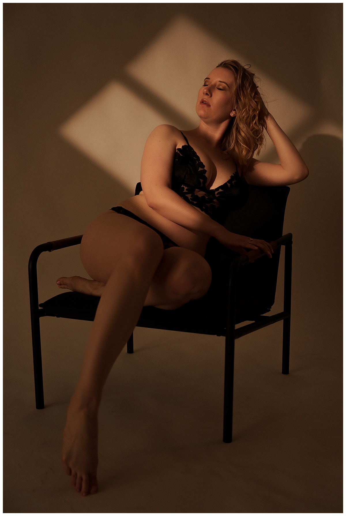 Woman sits on chair wearing black lingerie for Emma Christine Photography