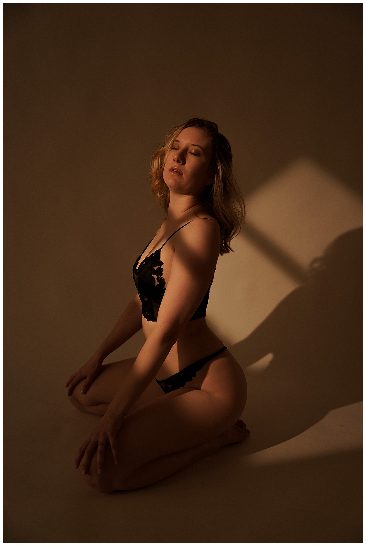 Adult kneels down wearing black lingerie for Emma Christine Photography