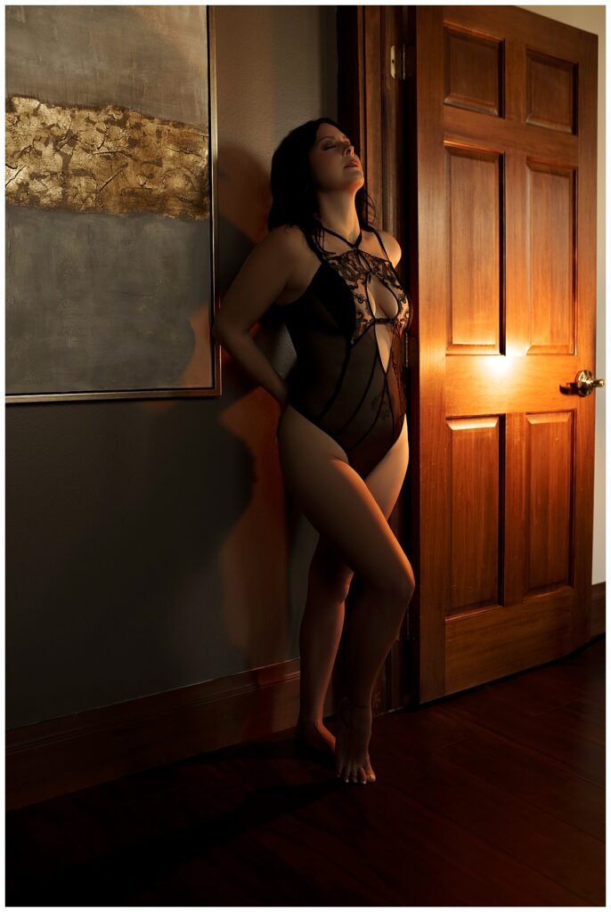 Female stands beside the doorframe for Sioux Falls Boudoir Photographer