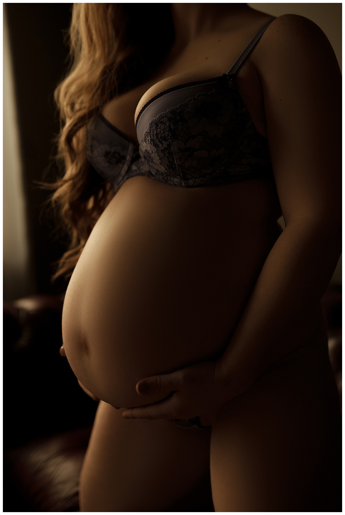 Female embraces her pregnant belly for Emma Christine Photography