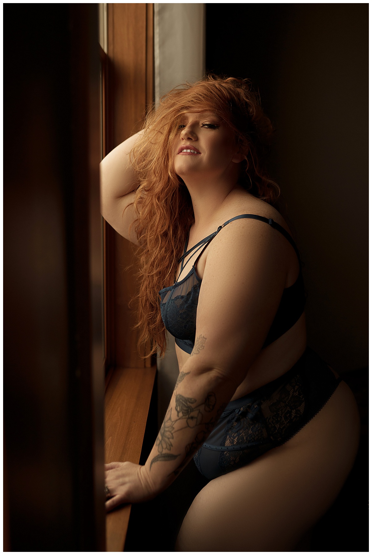 Woman stands against the winfow for Sioux Falls Boudoir Photographer