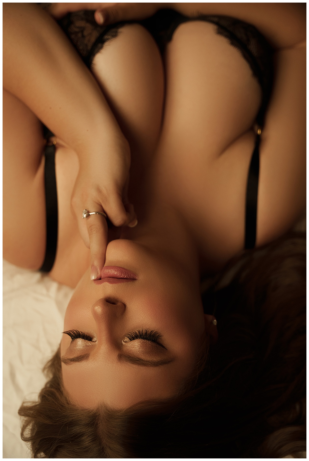 Woman lays down with finger to her mouth after reviewing ways to be Preparing Your Mindset for your boudoir session