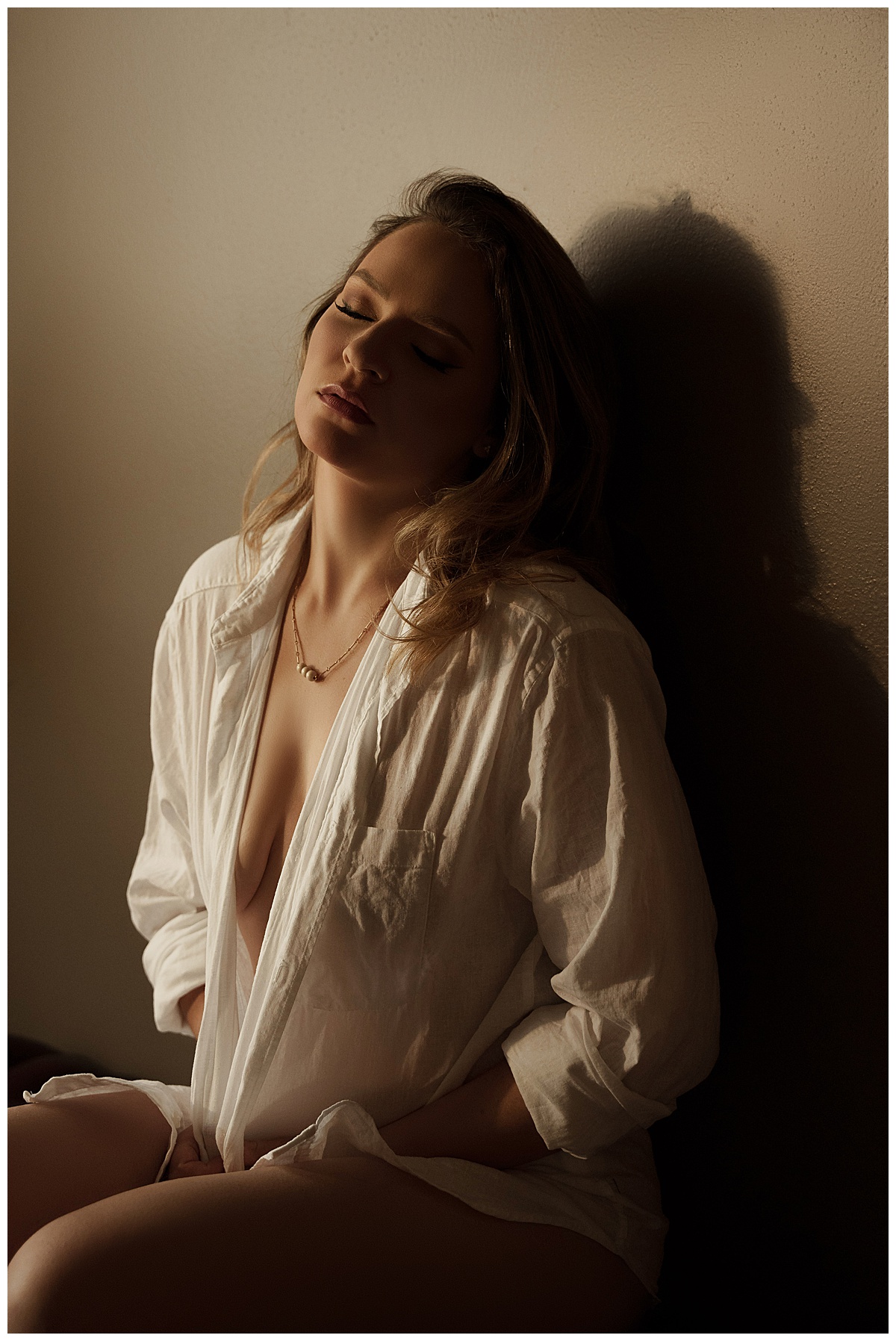 Adult sits on the floor wearing a white shirt showing how you can Fall In Love With Yourself when you book a boudoir session