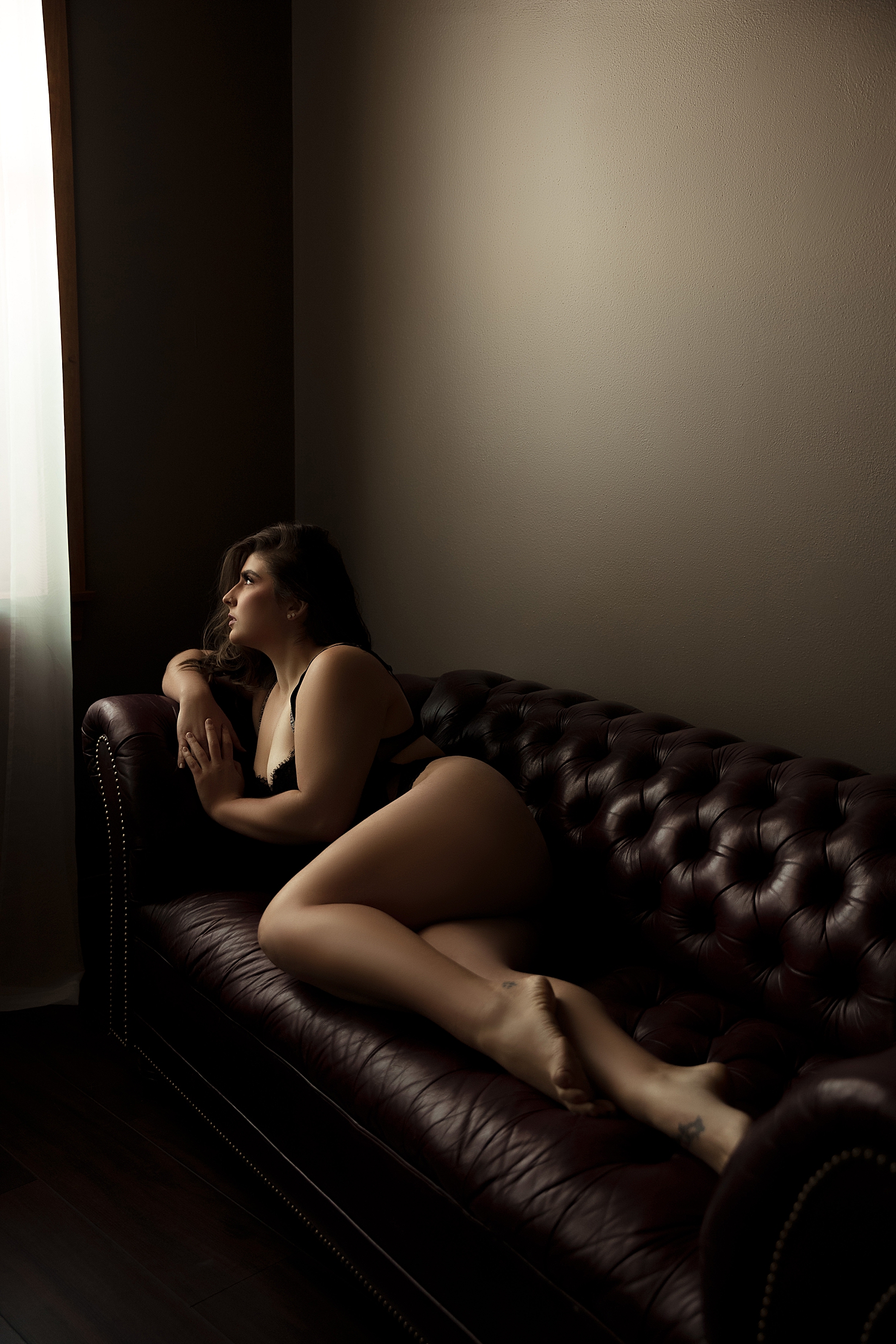 model with tattoos on a couch by Sioux Falls Boudoir Photographer