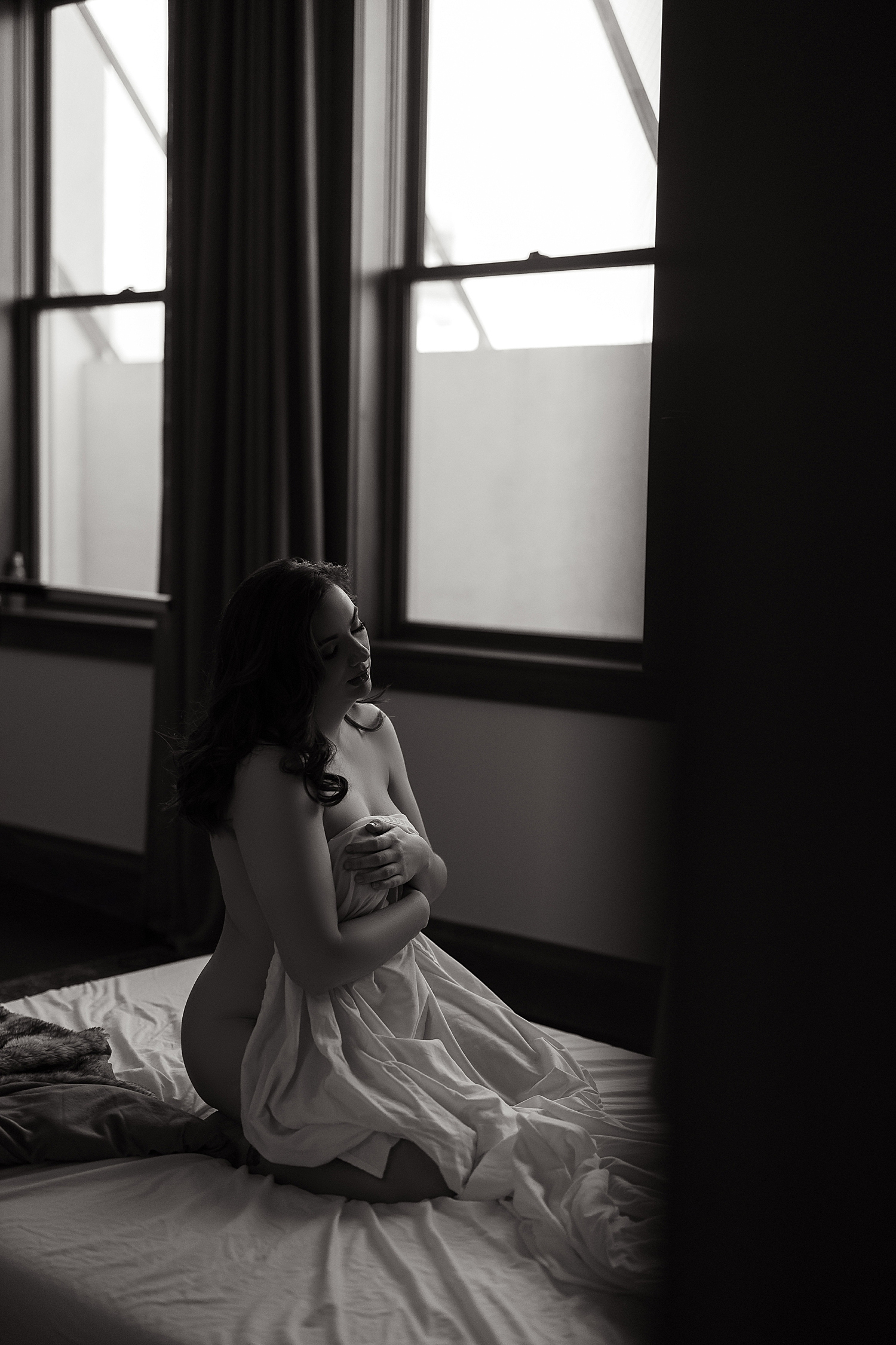 model kneels on mattress and covers with sheet by Emma Christine photography 