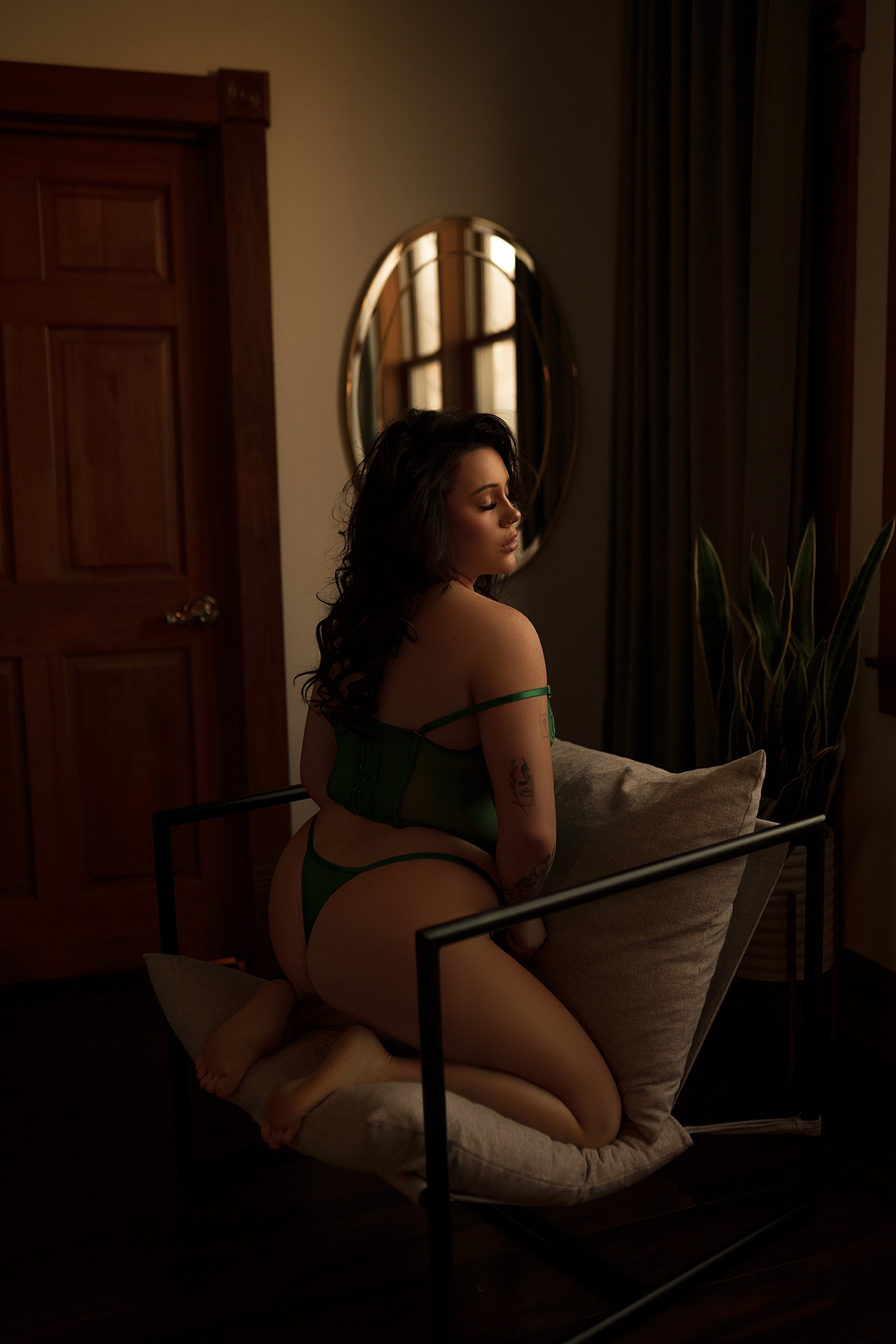 person with tattoos wearing two piece lingerie on chair by Sioux Falls boudoir photographer