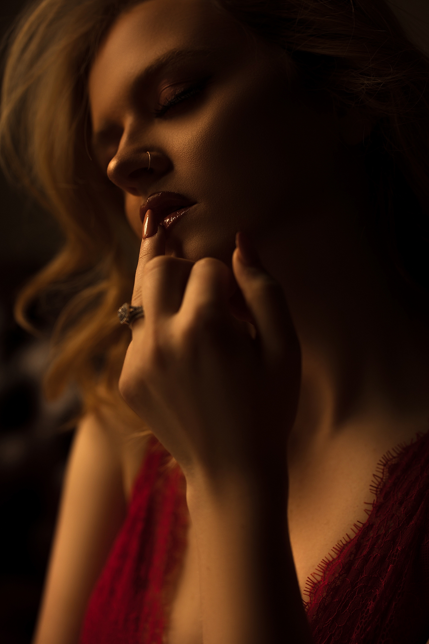woman touches her maroon lips seductively by Emma Christine Photography