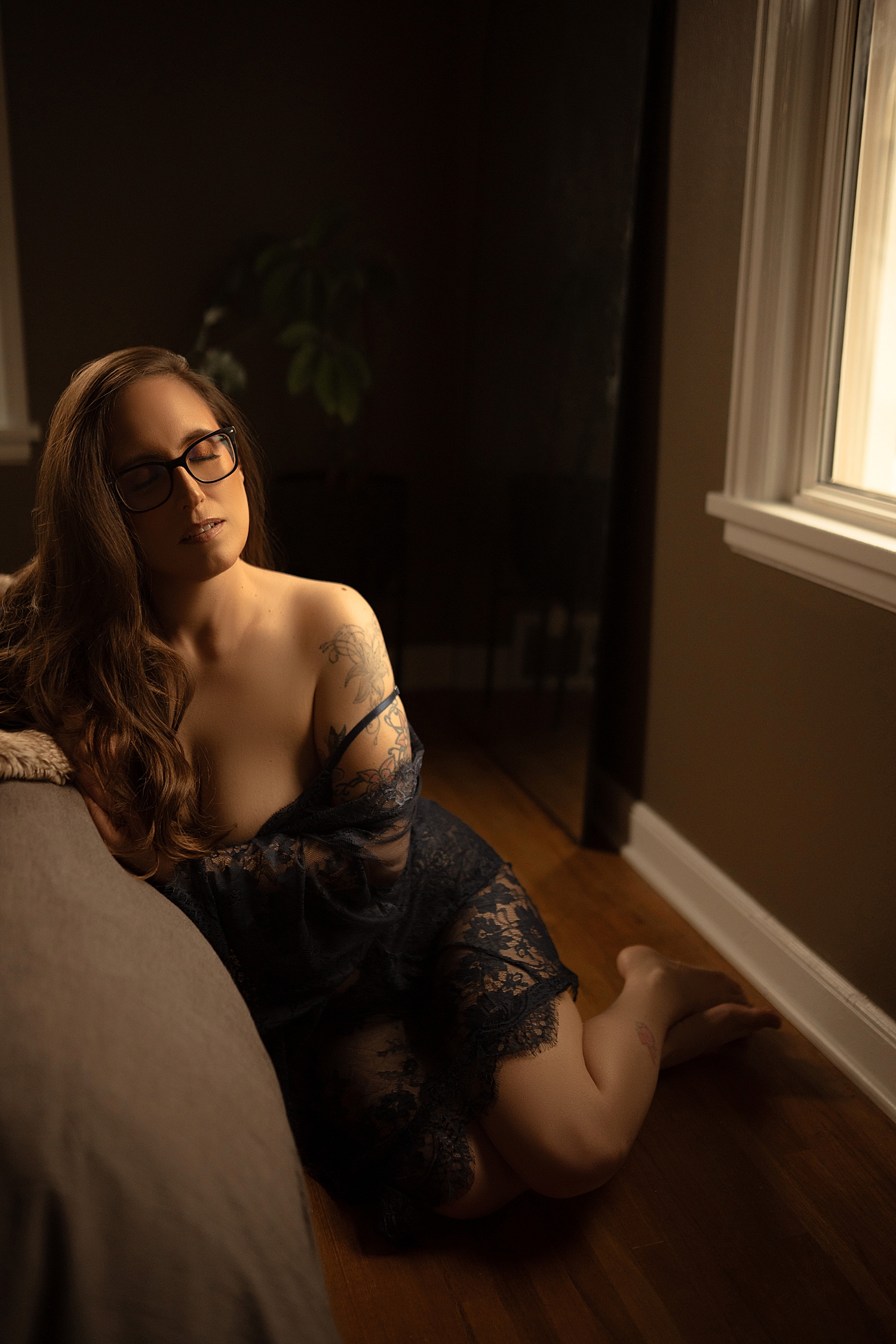 MILF sits on floor next to window in lace robe by Sioux Falls Boudoir Photographer 
