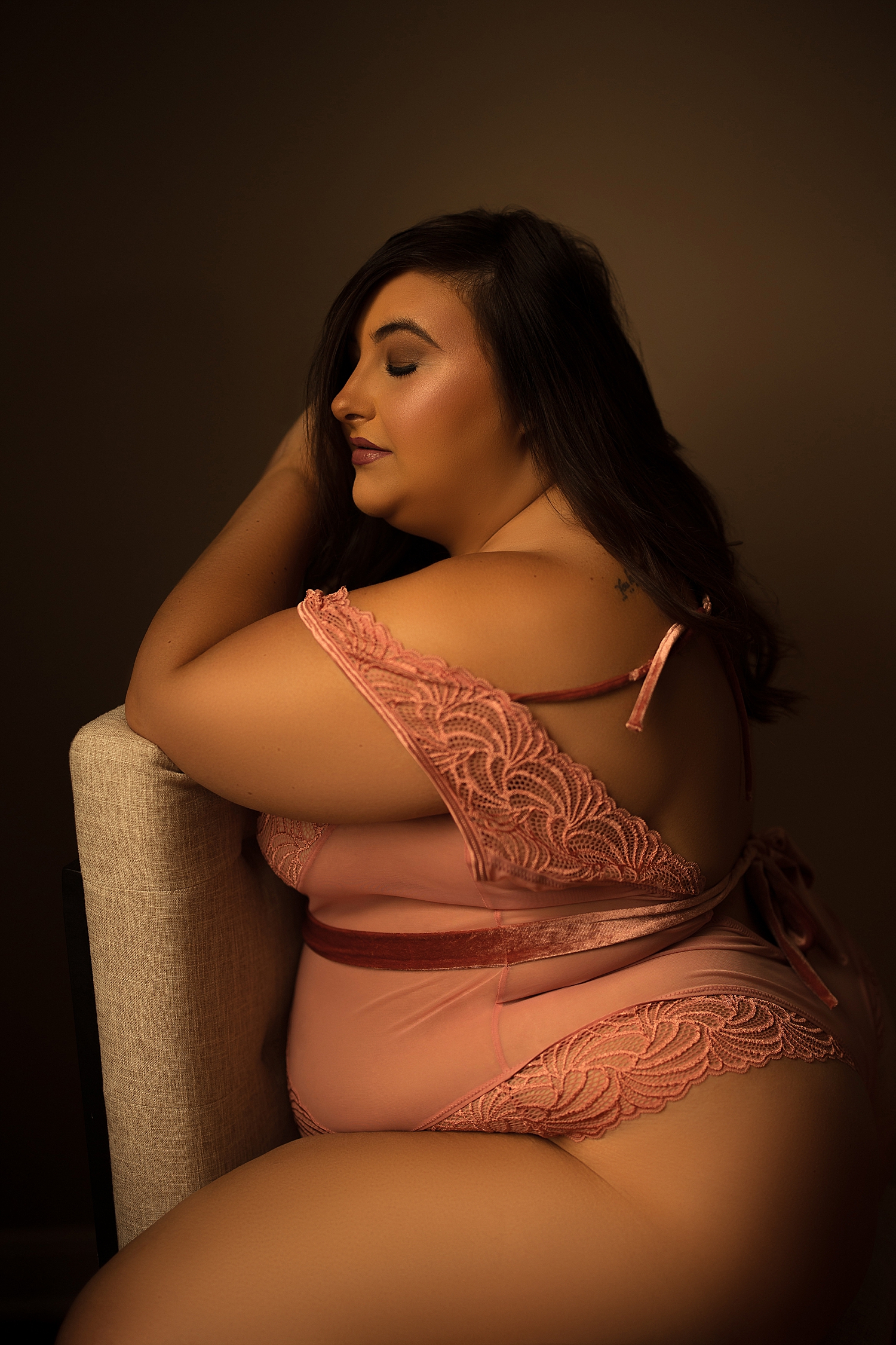 brunette leans against chair in pink outfit by Emma Christine Photography 