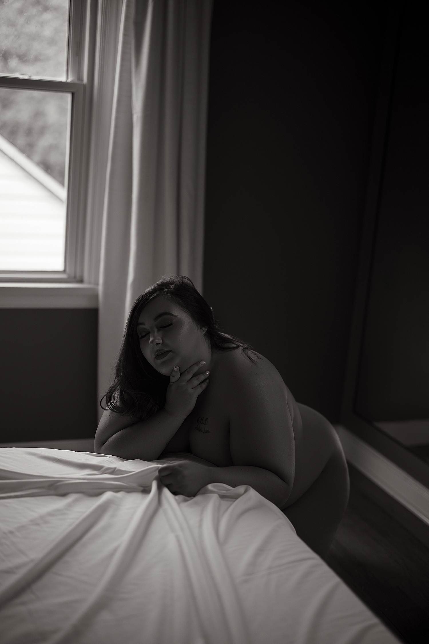 nude woman leans over bed for photo shoot overcoming insecurity 
