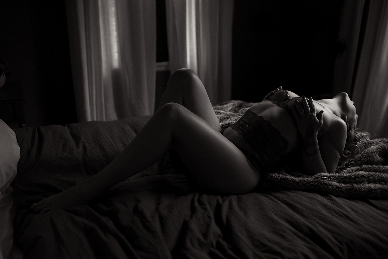model lies across bed in lace lingere by Emma Christine Photography