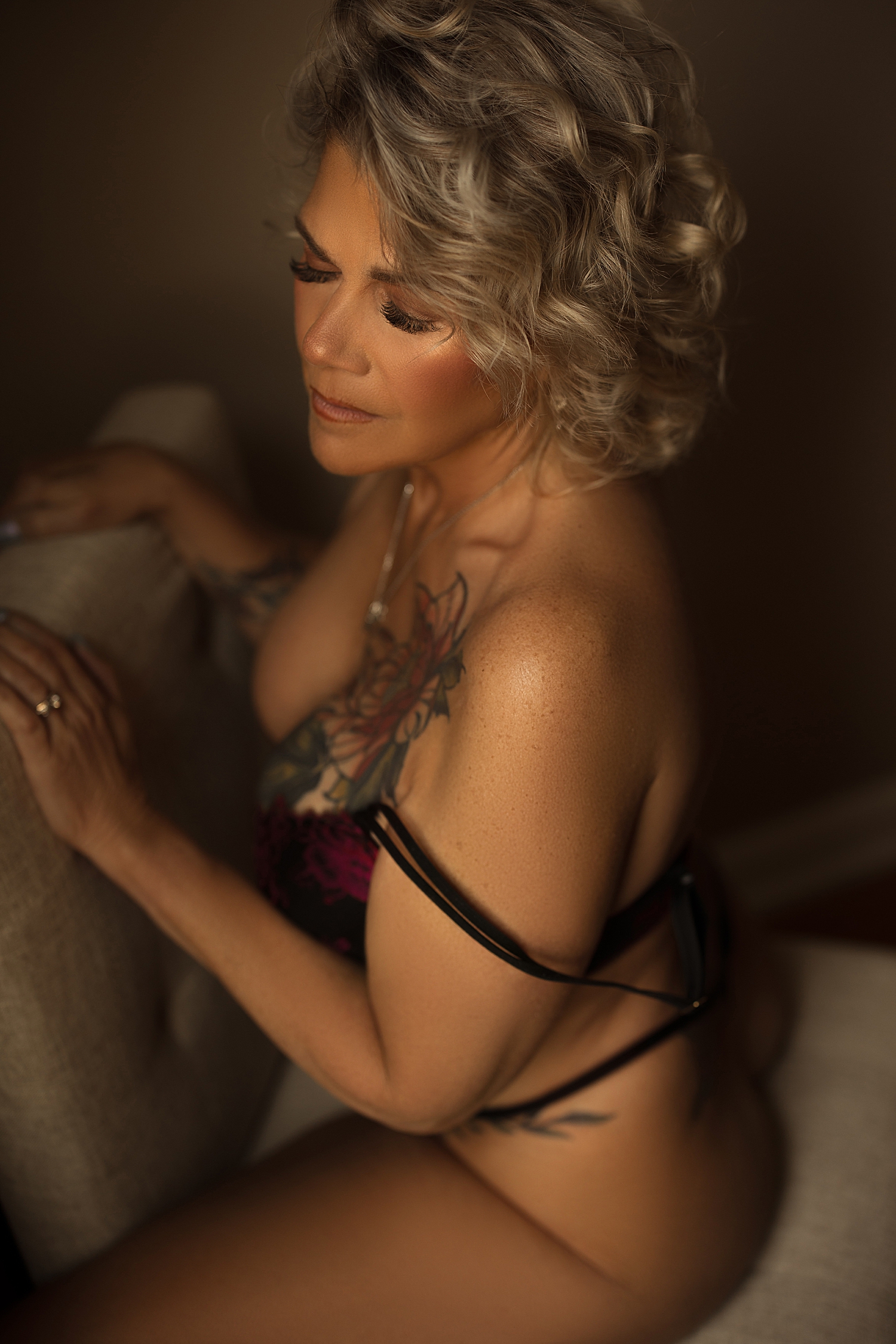 cool blonde with short hair stradles a chair in the studio by Sioux Falls boudoir photographer