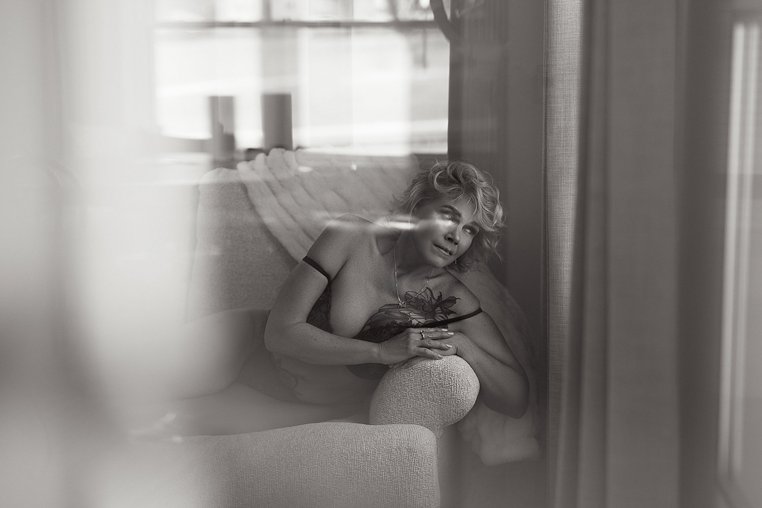 older woman lies across couch in bra by Emma Christine photography