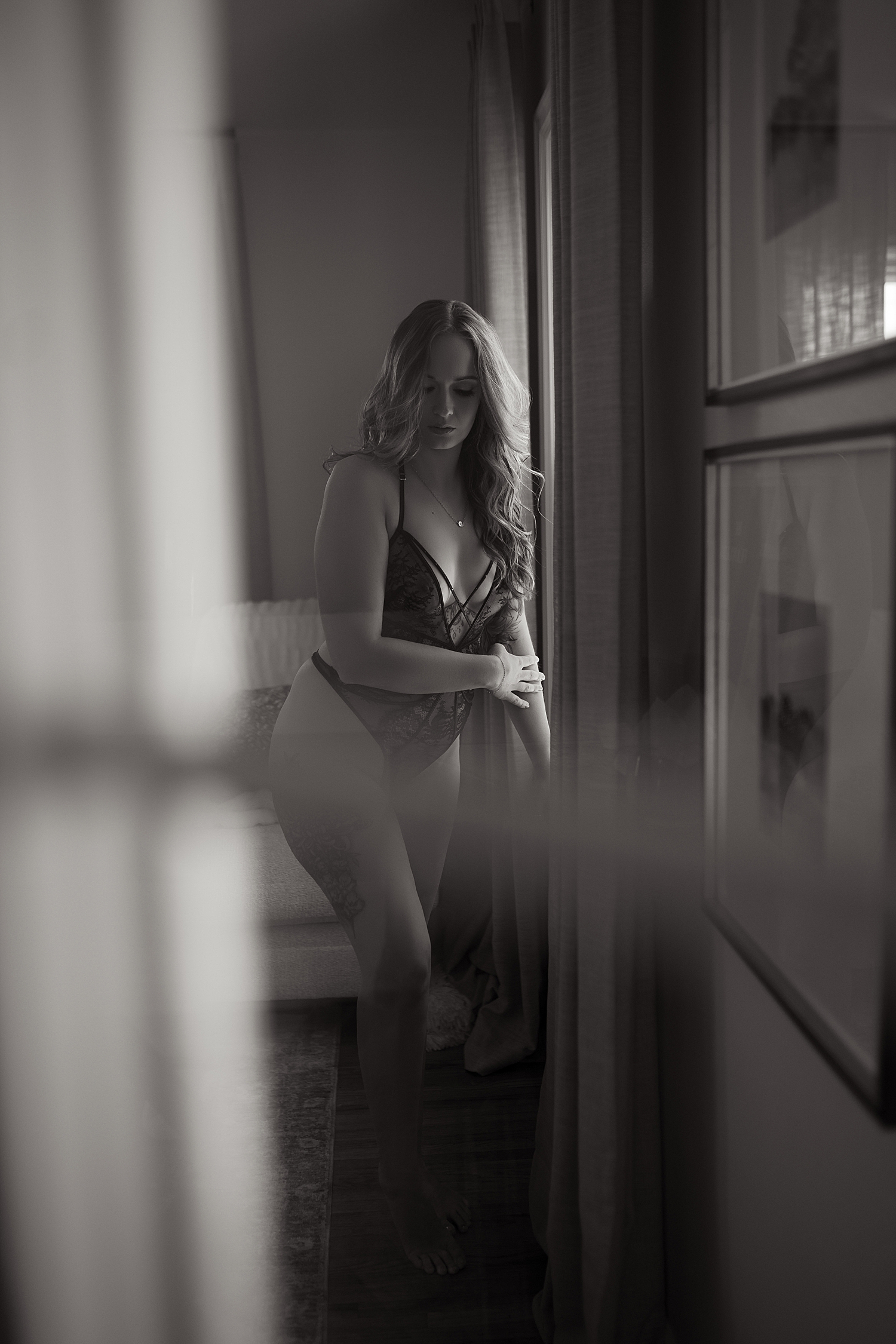 blonde in lace bodysuit next to window by Sioux Falls Boudoir Photographer